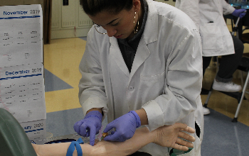 student drawing blood from a dummy