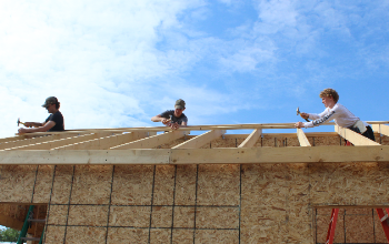 three students working on roof