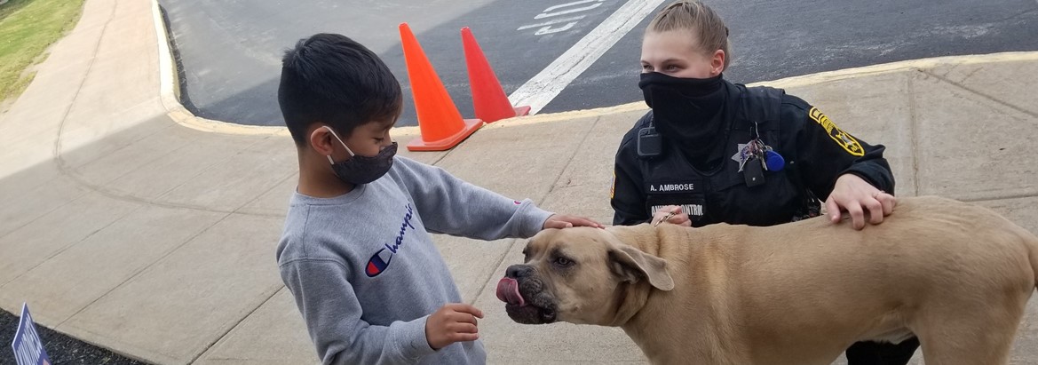 boy petting dog with police officer nearby