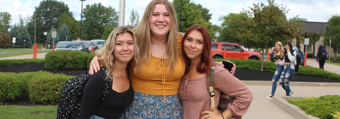 three girls standing with arms around each other