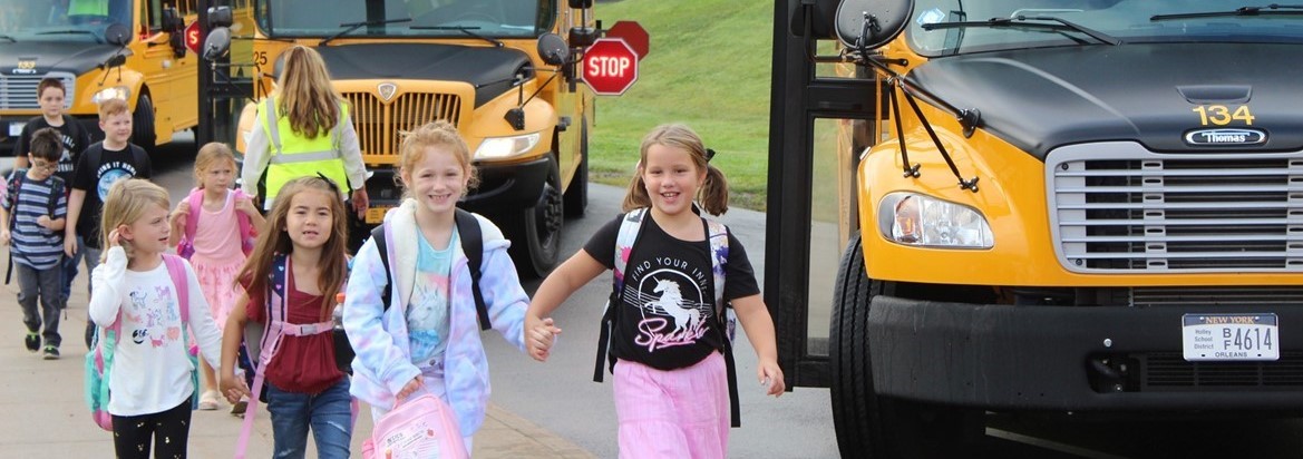 kids walking down sidewalk near buses