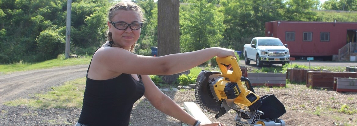 girl using circular saw to cut board