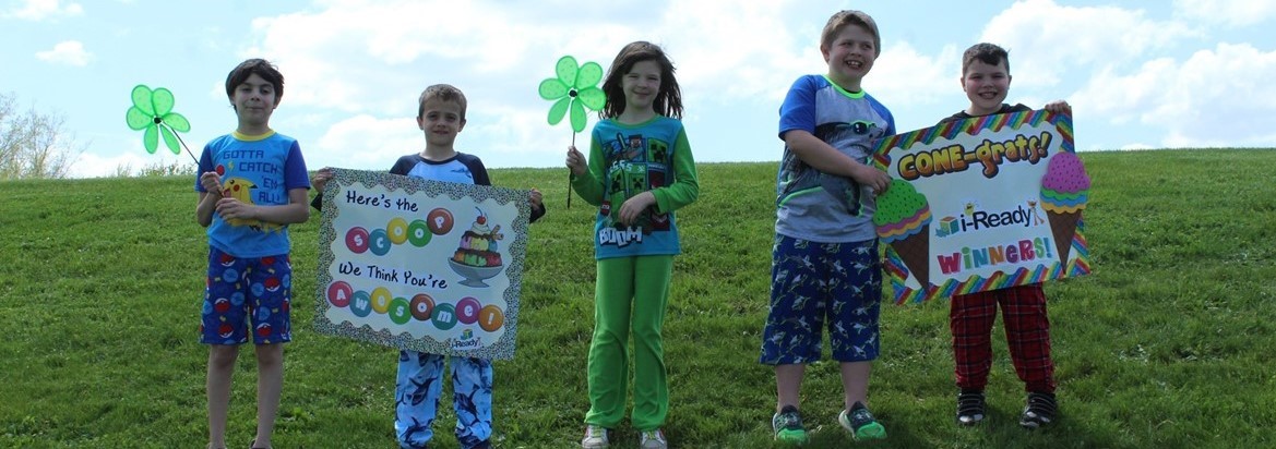 students standing on hill holding signs or whirligig flowers