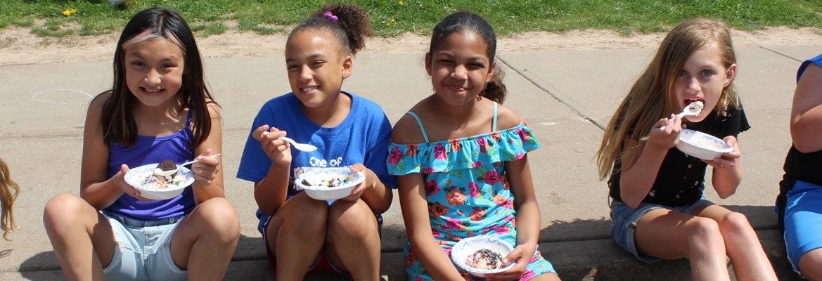girls sitting on curb eating bowls of ice cream