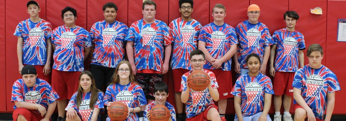 unified basketball team standing, sitting or kneeling, some holding basketballs