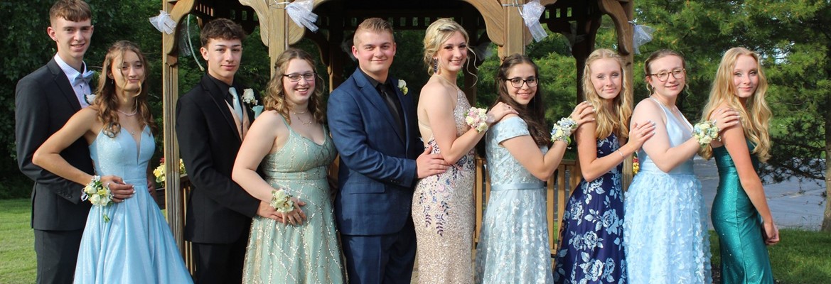 group of boys and girls in prom attire standing near gazebo