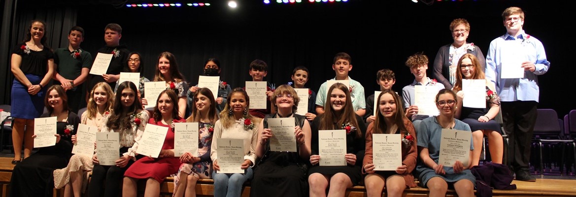 national junior honor society inductees standing or sitting holding their certificates