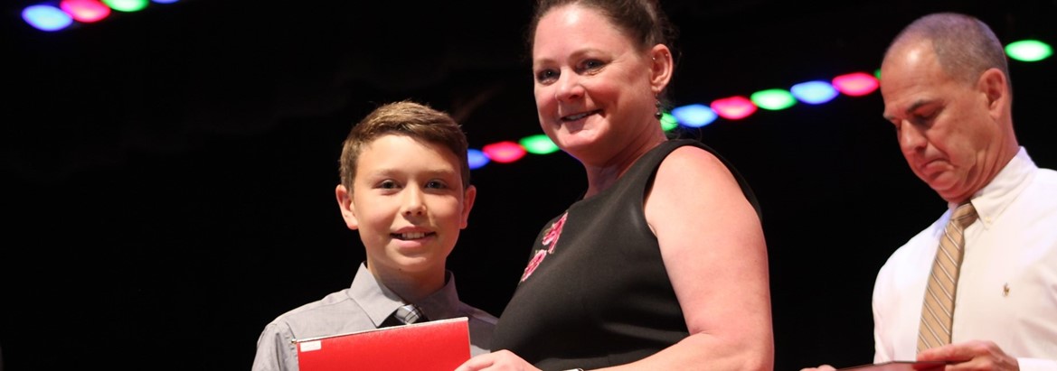 boy posing with diploma next to principal