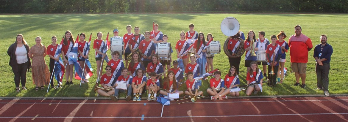 marching band students and staff standing or sitting on field