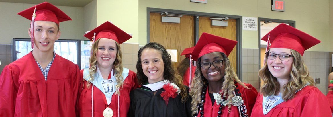 students in caps and gown standing with teacher