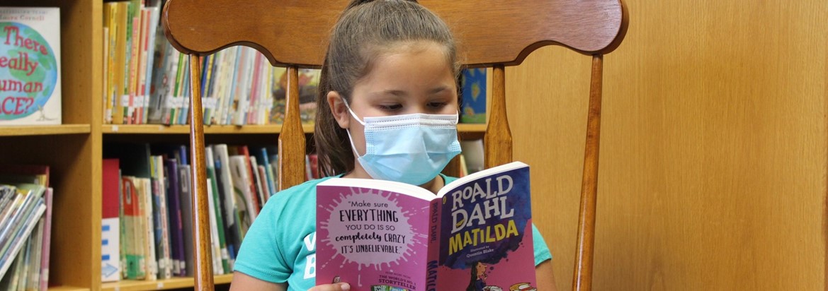 girl sitting in chair reading a book