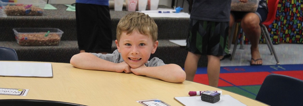 student smiling kneeling by table